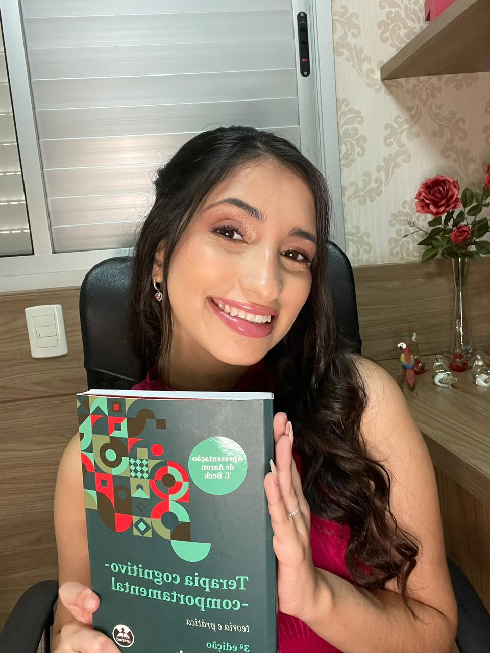 Kamilly Arantes segurando o livro Terapia Cognitivo-Comportamental: teoria e prática